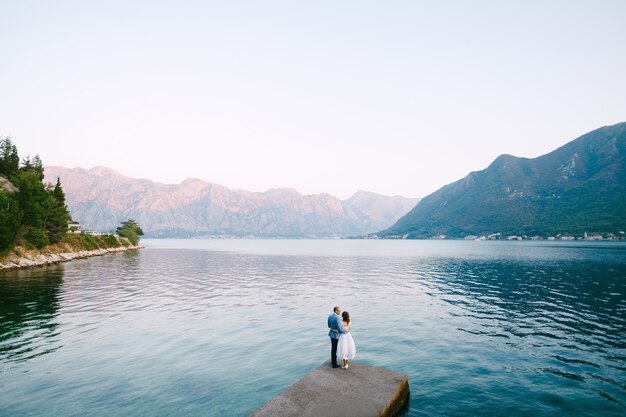 Lo sposo abbraccia la sposa in piedi sul molo