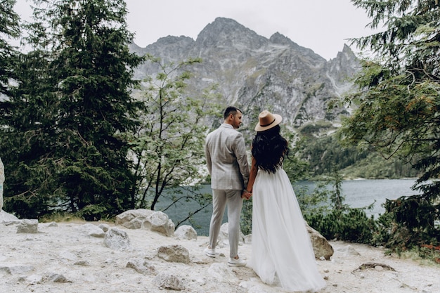 Groom hugs bride tender while wind blows her veil somewhere in Tuscany, Italy