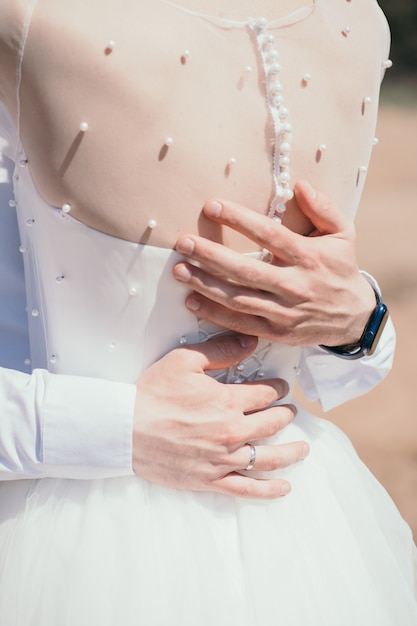 新郎は花嫁の花嫁の垂直写真を抱きしめ、花嫁の背中に美しいボタンを新郎します...