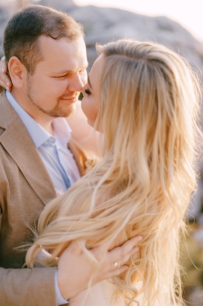 Groom hugs bride in a white dress closeup