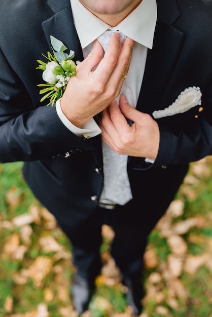 Groom is holding hands on the tie, wedding suit