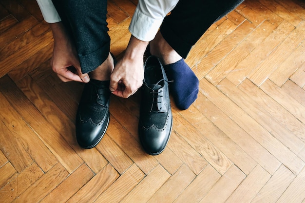 Groom is wearing the shoes Stylish man getting clothed Vintage style Wedding day