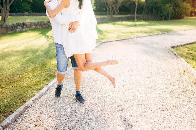 The groom lifted the bride in his arms legs closeup wedding