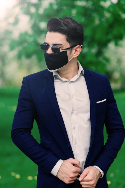 Groom in medical mask before wedding ceremony in the park outdoors.