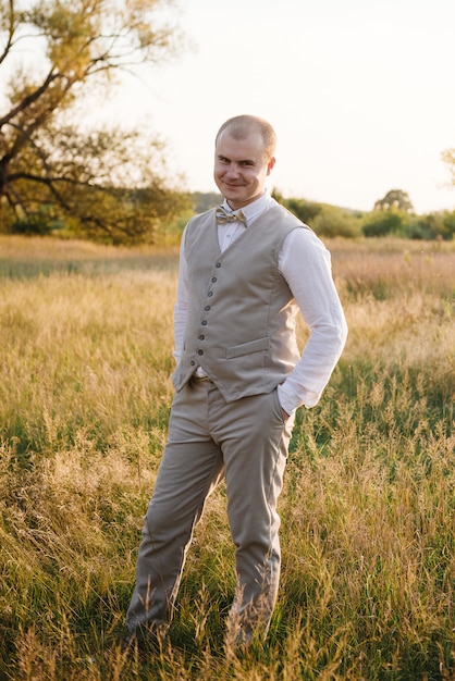 groom posing in the field at sunset