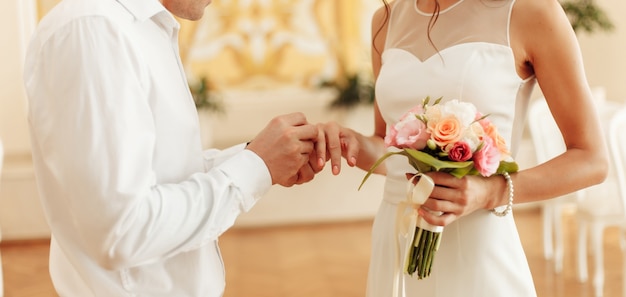 Жених надевает на палец невесты золотое кольцо. Свадебная церемония