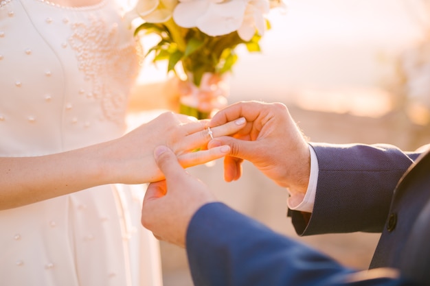 The groom puts the ring on the bride's finger during the wedding ceremony.  