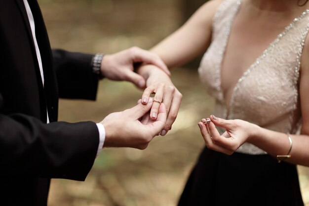 groom puts the ring on a young brides hand.