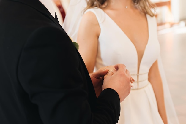 The groom puts a wedding ring on the bride's finger and the priest reads the text from the Bible The wedding ceremony in the church