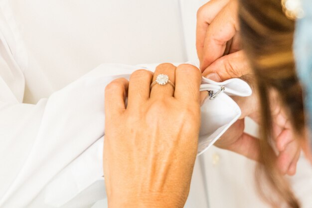 A groom putting on cuff-links as he gets dressed in his wedding day. Groom's suit