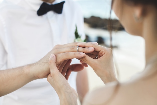 Groom putting a ring on bride's finger during wedding ceremony