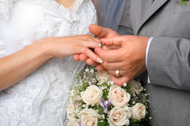 Groom putting wedding ring on bride's finger