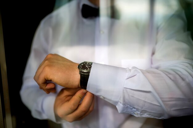 I preparativi dello sposo per il matrimonio. lo sposo abbottona la giacca. nozze foto in bianco e nero concetto. avvicinamento.