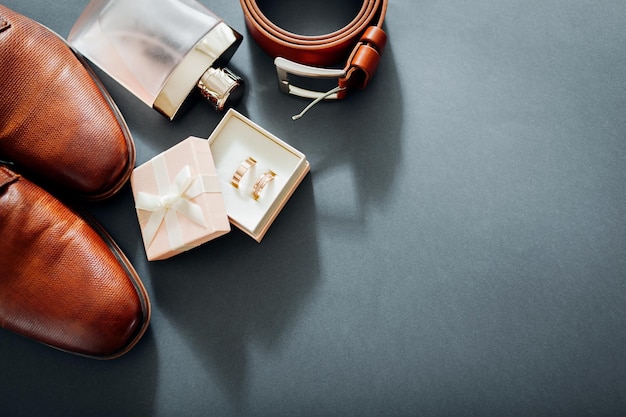 Фото Аксессуары в день свадьбы жениха коричневые кожаные туфли ремень духи золотые кольца в коробке мужская мода