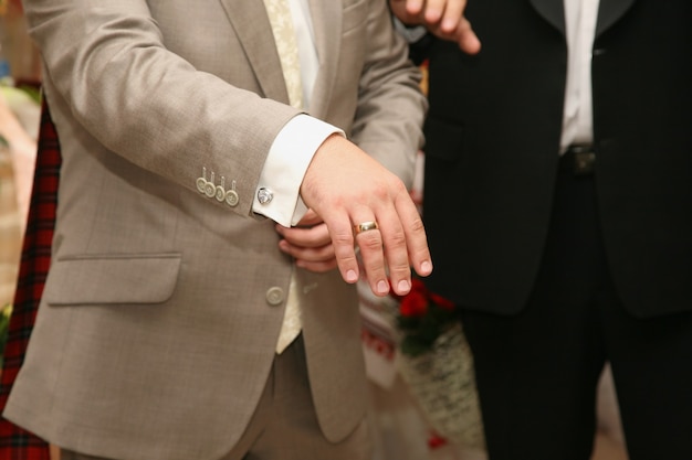 The groom shows the wedding ring on his hand