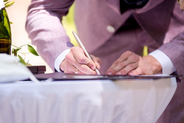 Foto lo sposo firma la licenza di matrimonio. cerimonia della firma. tradizione del matrimonio.