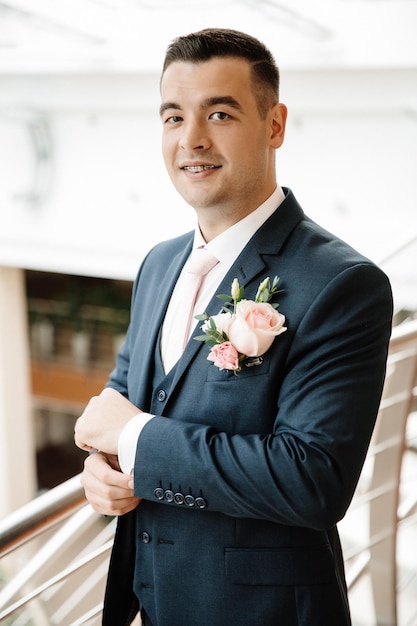 The groom smiles and straightens the cufflink on his sleeve