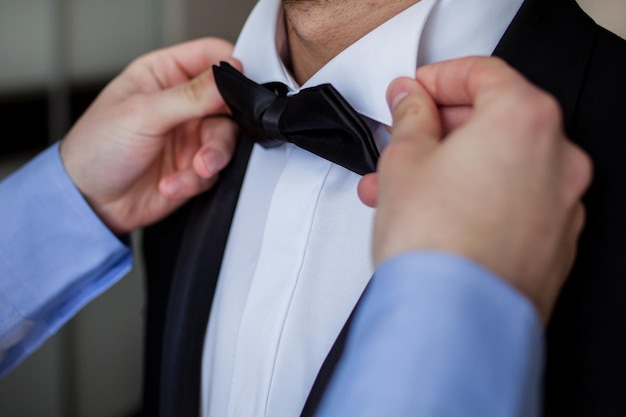 The groom straightens the bow tie. Man straightening his black bow-tie. Getting Ready. wedding