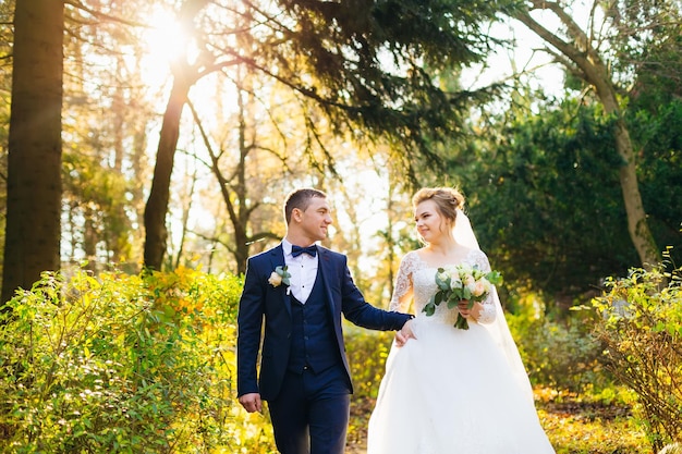 Жених в стильном костюме держит невесту за руку и смотрит