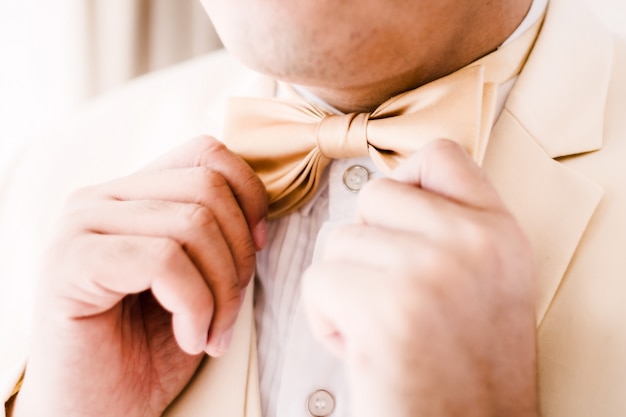 Groom touching bowtie