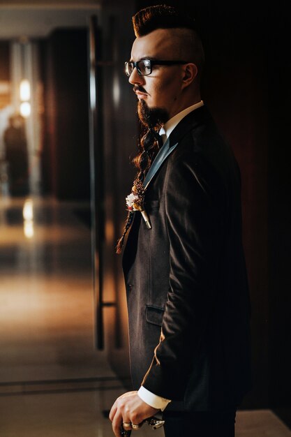 The groom in a tuxedo and bow tie with a mohawk hairstyle and a cane in the interior