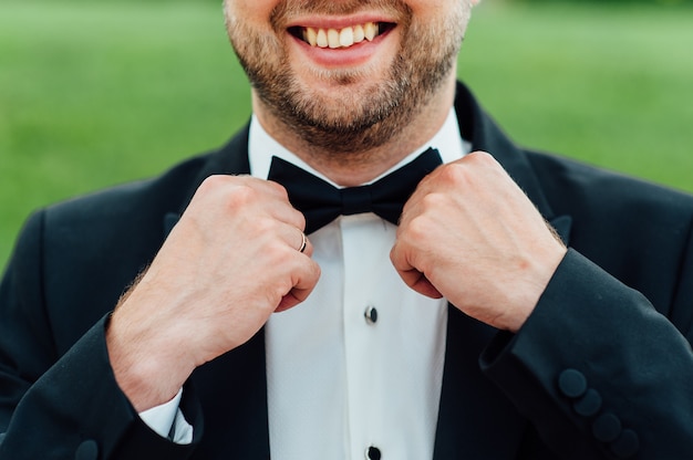 Groom tying tie on a white shirt