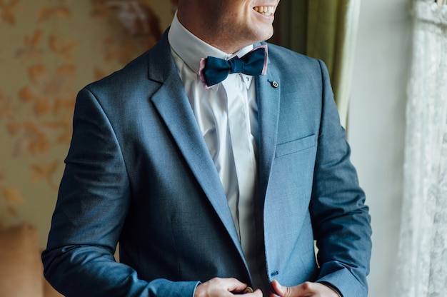 Groom tying tie on a white shirt