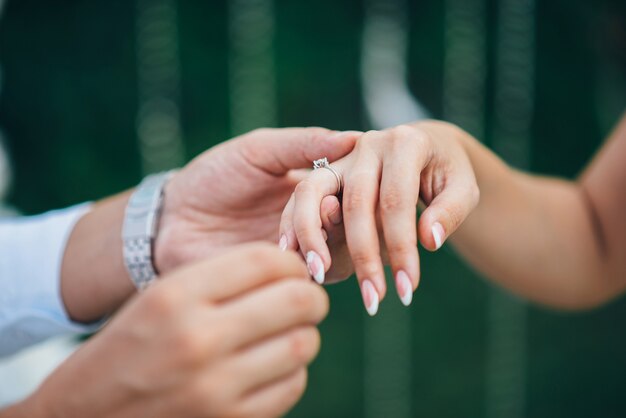 Groom in a watch and a suit puts the wedding ring on the bride's finger