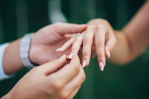 Groom in a watch and a suit puts the wedding ring on the bride's finger