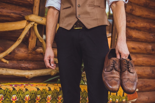A groom and wedding shoes. Groom is wearing shoes outdoors. Male portrait of handsome guy.