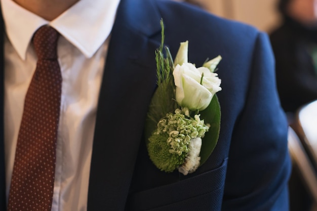 Groom at a wedding with a boutonniere of white eustoma