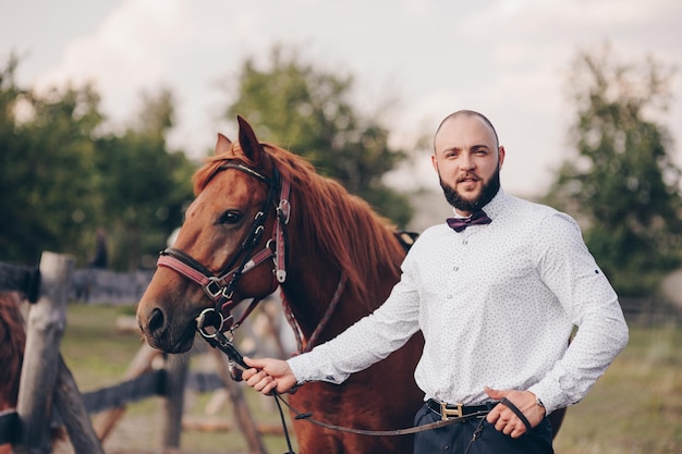 The groom in a white shirt and a purple bow tie. Horse riding.