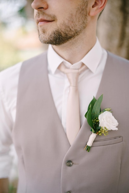 Groom in a white shirt tie and vest with a boutonniere closeup