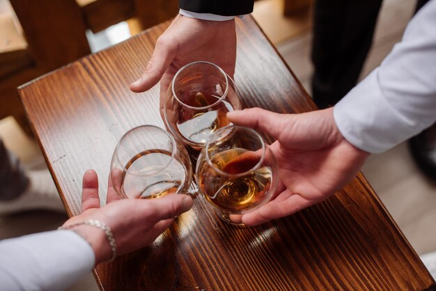 Groom with bestmen drinks whiskey from glasses Closeup