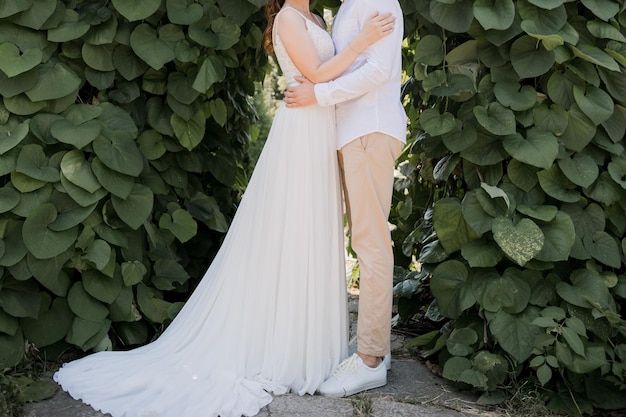 Groom with bride in wedding dress in summer park