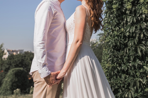 Groom with bride in wedding dress in summer park