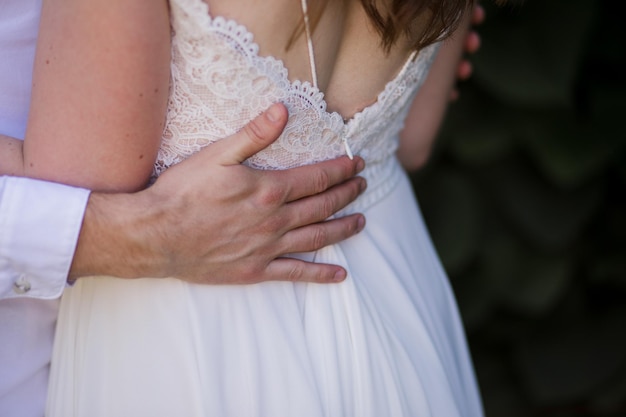 Жених с невестой в свадебном платье в летнем парке