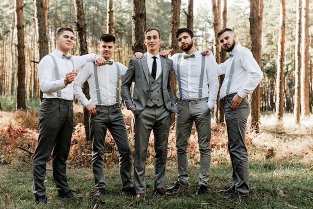 Groom with friends hold hands in pockets and look at the camera