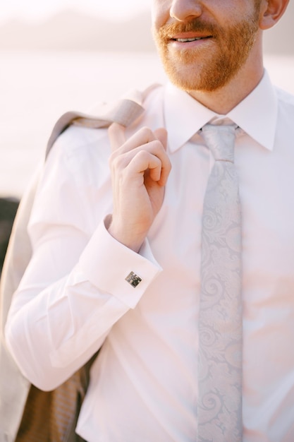 Groom with a jacket on his shoulder on the seashore portrait