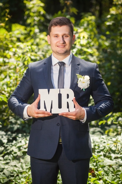 Photo groom with sign mr standing in the forest