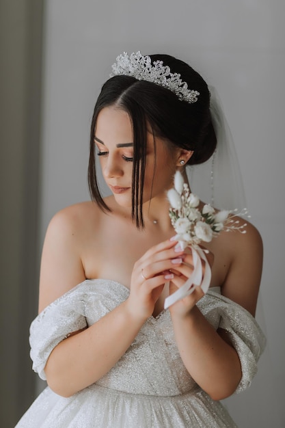 the grooms boutonniere is arranged from rose flowers in the hands of the bride with a French manicure in the wonderful natural light from the window