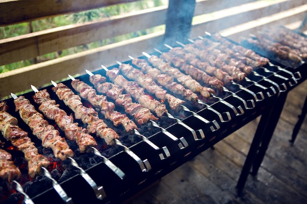 Groot aantal bereiden kebabs op de grill met kolen en rook onder een luifel