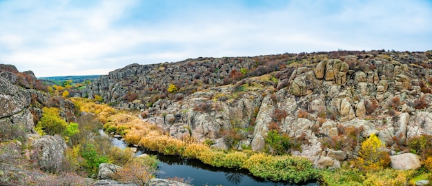 Groot aantal steenmineralen bedekt met groene vegetatie, liggend boven een kleine rivier in het pittoreske Oekraïne en zijn prachtige natuur