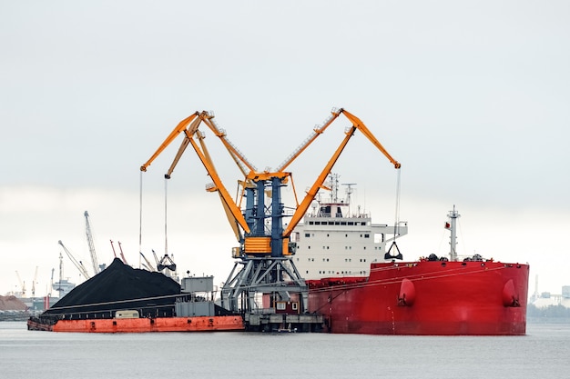 Groot rood vrachtschip laden met een kolen in de haven