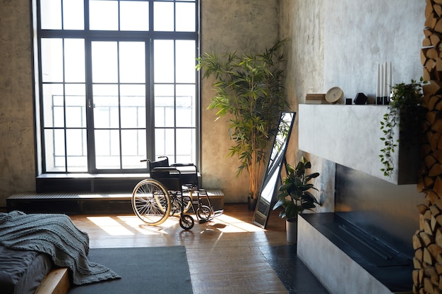 Groothoekbeeld van lege rolstoel in modern appartement interieur verlicht door zonlicht, kopieer ruimte