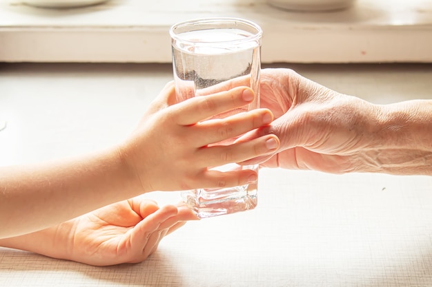 Grootmoeder die een glas schoon water geeft aan een kind. Selectieve aandacht. natuur.