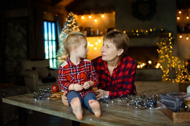 Grootmoeder en kleindochter in een gezellige, ingericht voor kerst huis, op zoek naar elkaar.