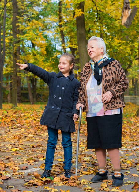 Grootmoeder en kleindochter wandelen in het herfstpark