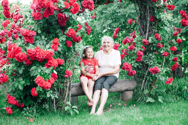 Grootmoeder en kleindochter zitten blootsvoets op een blokhut in de tuin