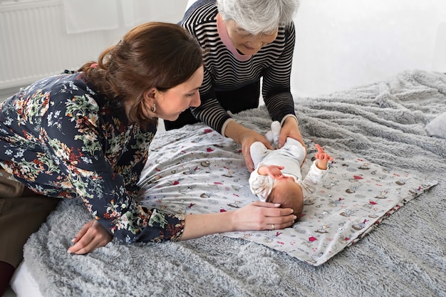 Grootmoeder en moeder zijn blije baby. Familieleden spelen met een pasgeborene